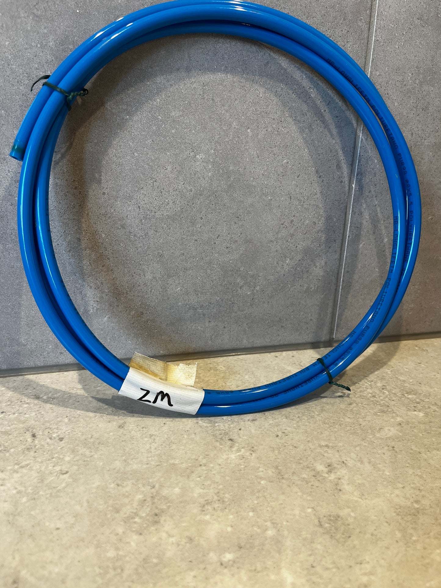Coiled blue polyurethane tubing on gray surface