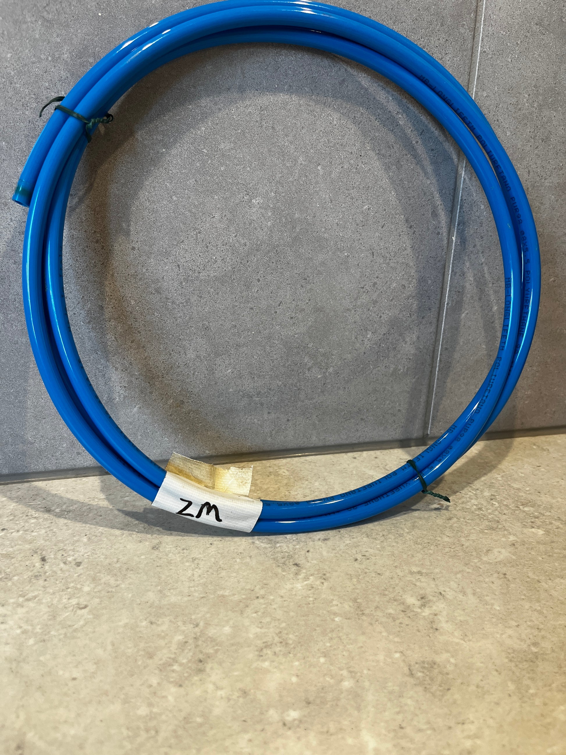 Coiled blue polyurethane tubing on gray surface