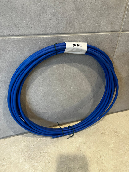 Coiled blue polyethylene tubing on tiled floor with a white label marked '8M'