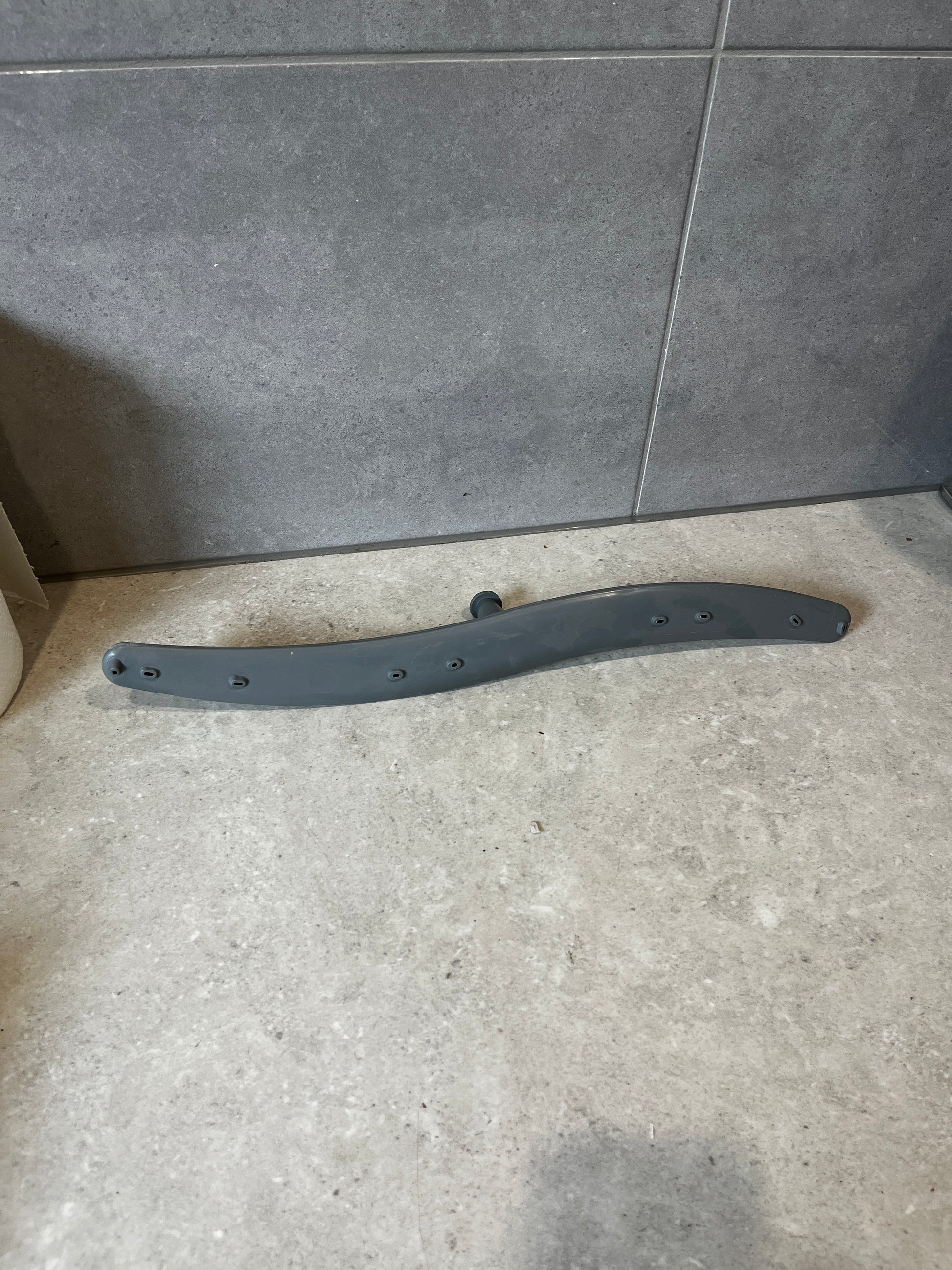 Gray dishwasher lower spray arm on a tiled surface