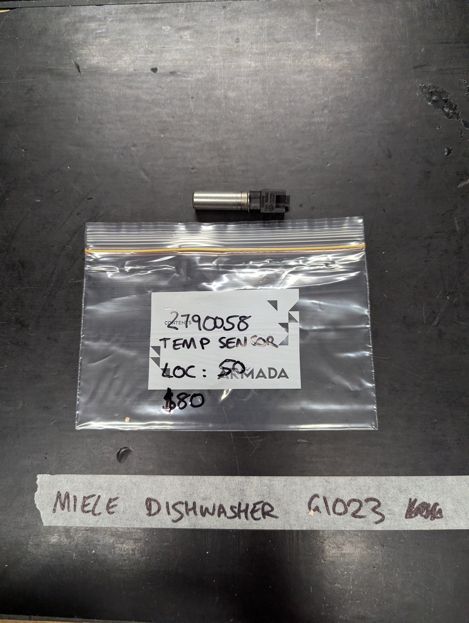 Miele Dishwasher G1023 temperature sensor with labeled bag on black surface