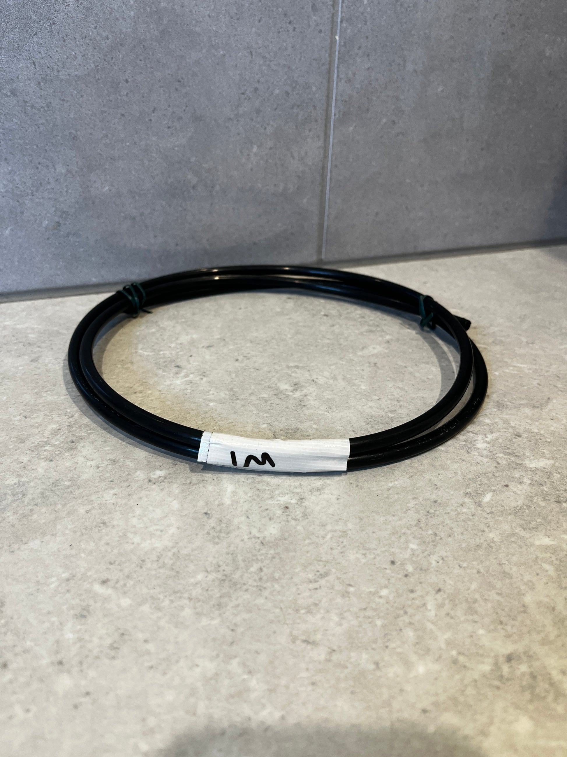 Coiled 1 meter black flexible tubing on countertop