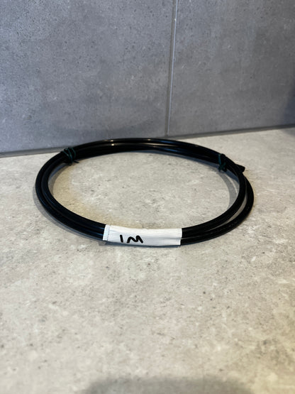 Coiled 1 meter black flexible tubing on countertop