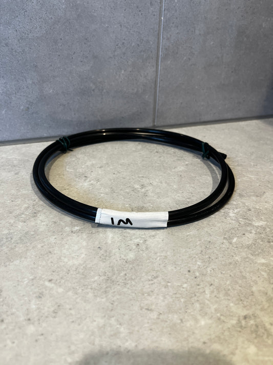Coiled 1 meter black flexible tubing on countertop