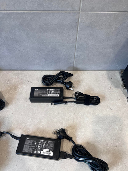 Multiple HP 120W laptop power adapters with power cords on a countertop