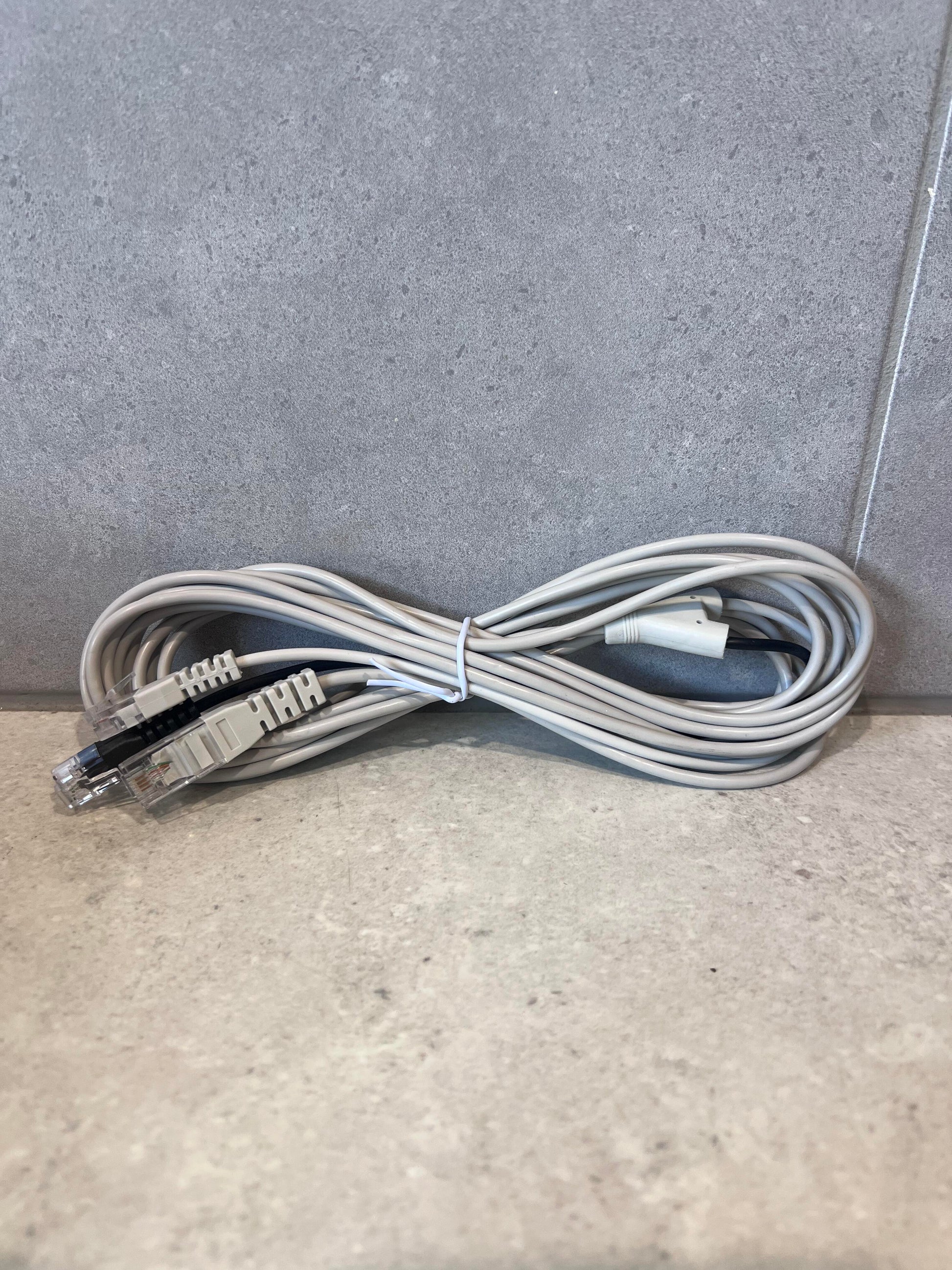 Coiled Ethernet patch cable with dual connectors on a gray surface