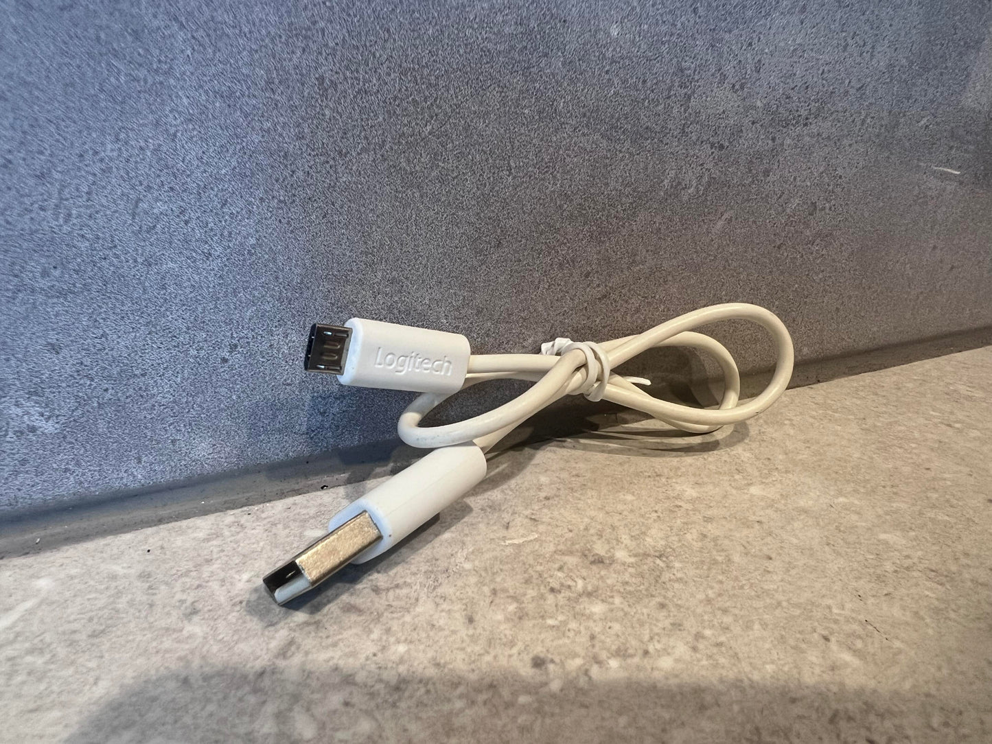 Logitech USB A to Mini-B cable coiled on a granite surface