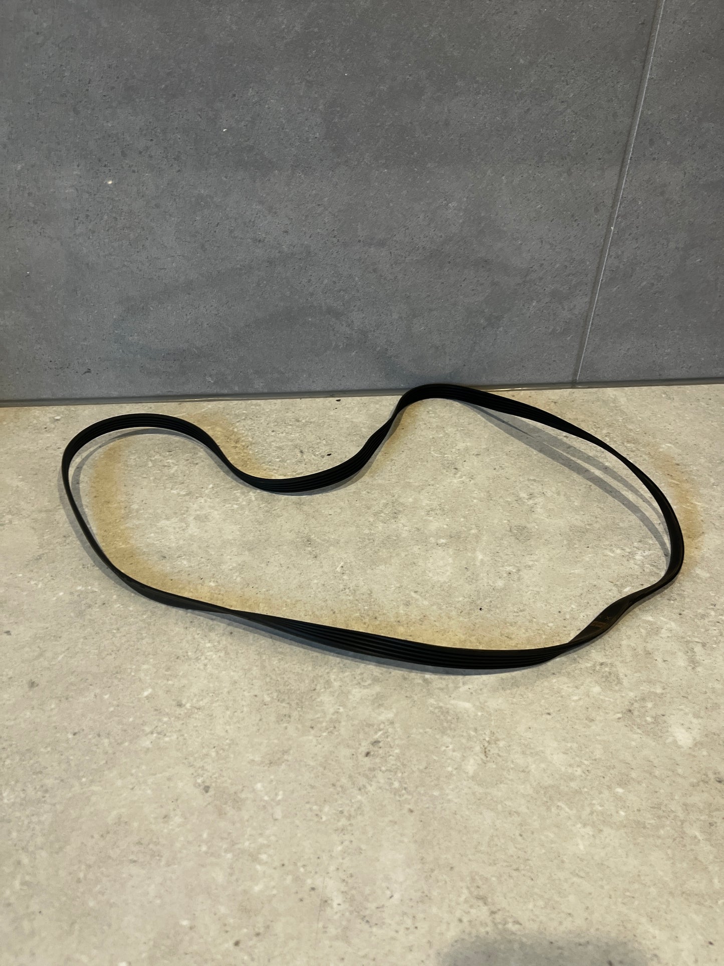 Black multi-rib serpentine belt on a light surface