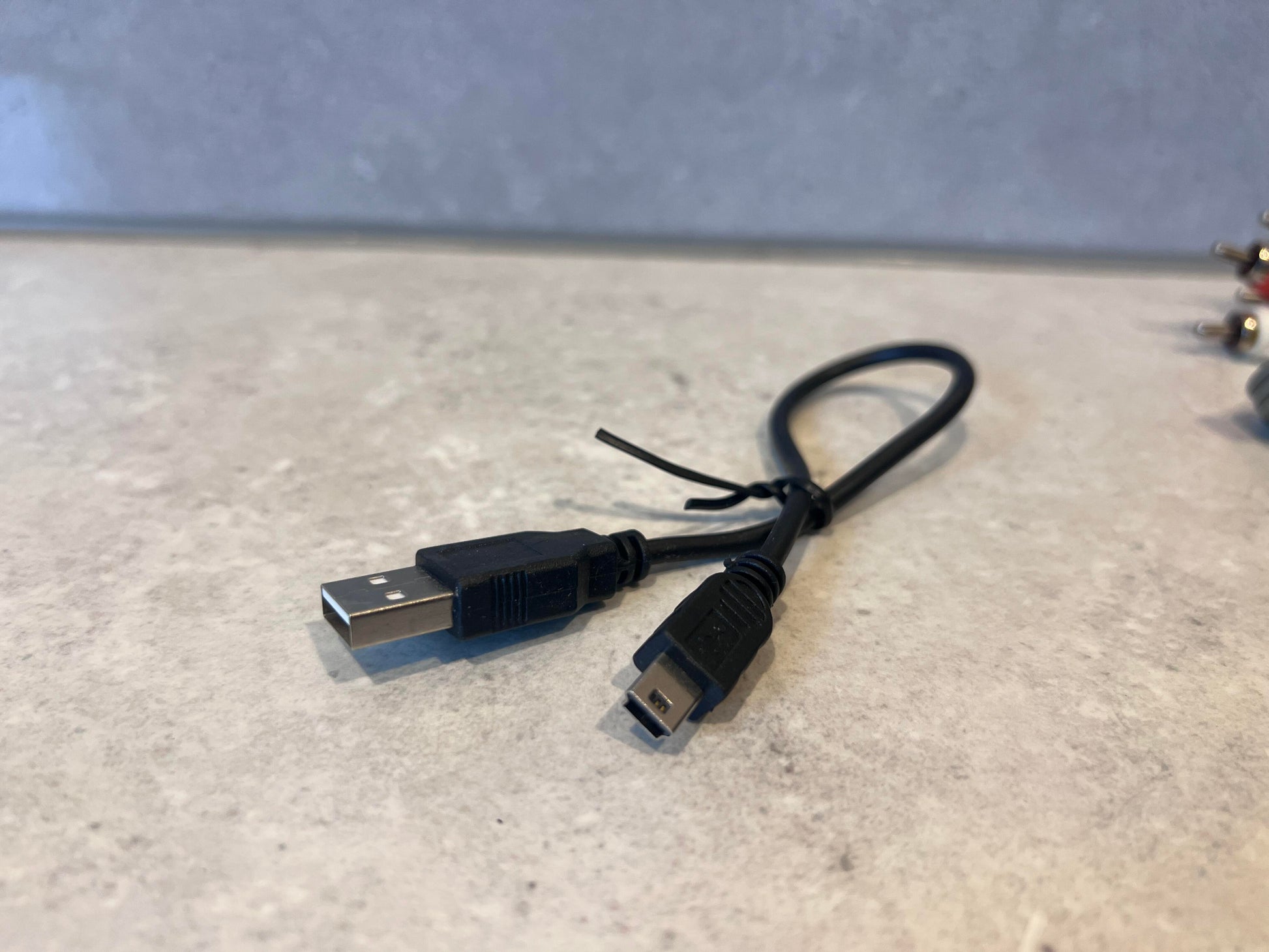 USB to Mini USB black charging cable on a countertop