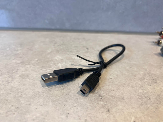 USB to Mini USB black charging cable on a countertop