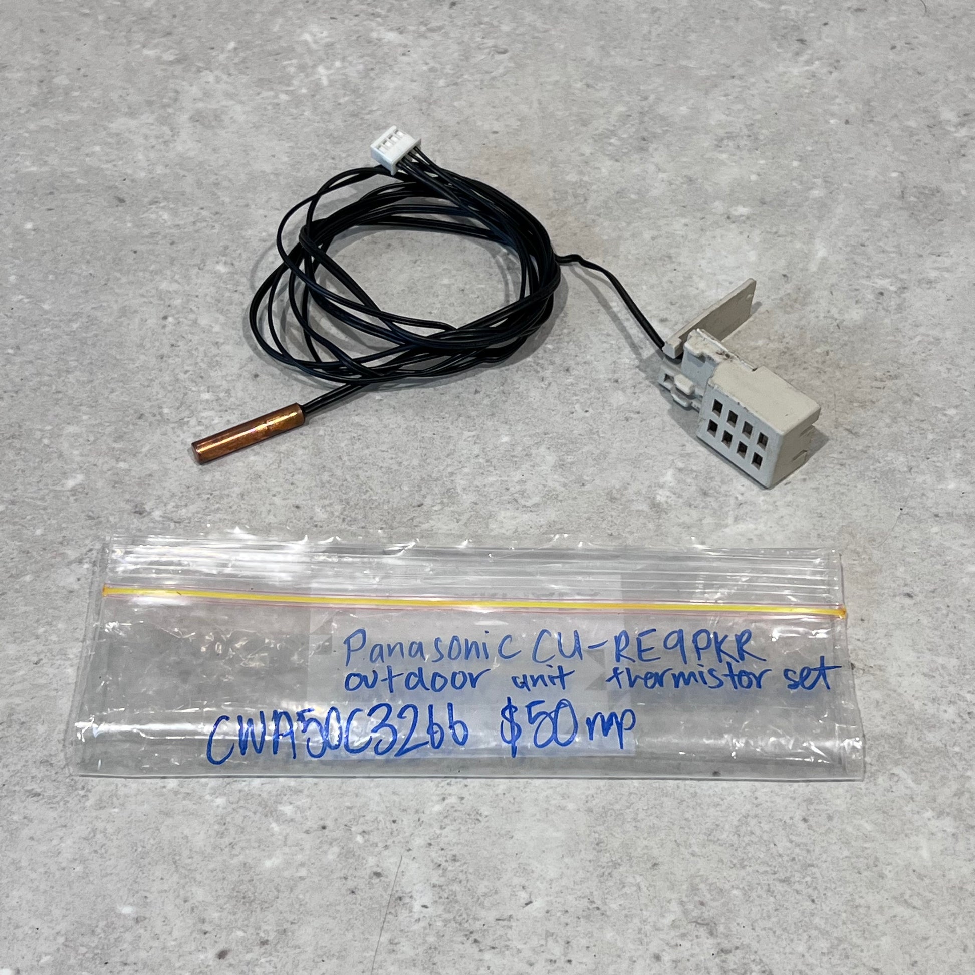 Panasonic CU-RE9PKR outdoor unit thermistor set with wires, copper probe, and sensor module on gray surface