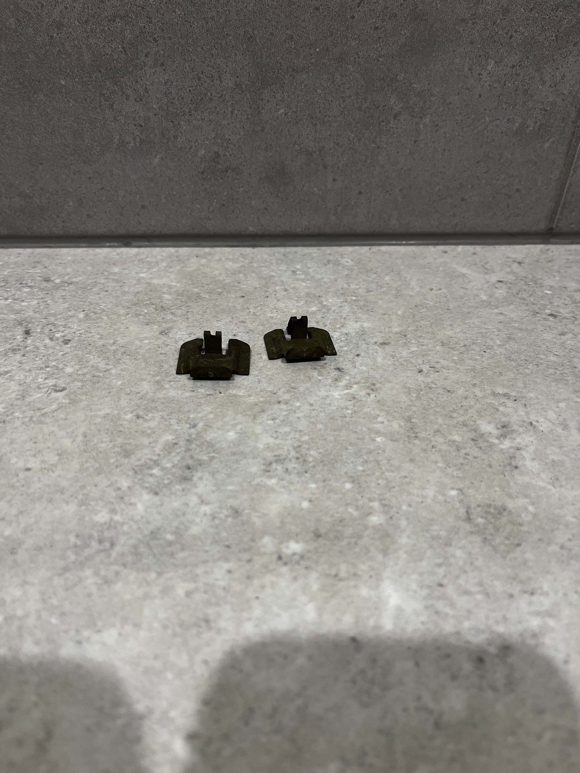 Pair of small metal clip fasteners on stone surface