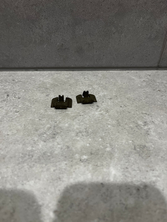 Pair of small metal clip fasteners on stone surface