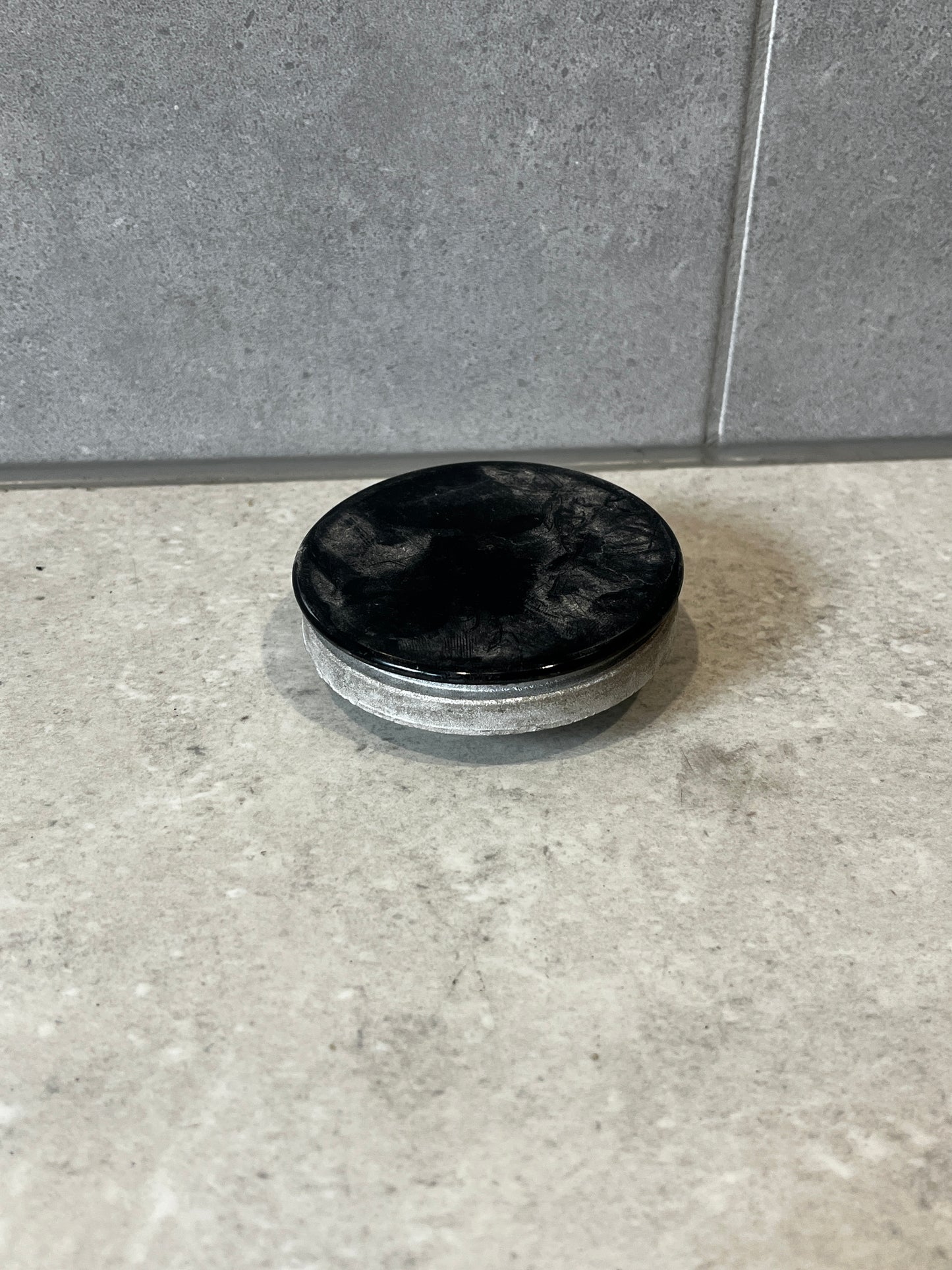 Round metal industrial end cap with black top and silver side on concrete surface