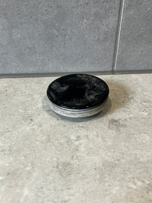 Round metal industrial end cap with black top and silver side on concrete surface