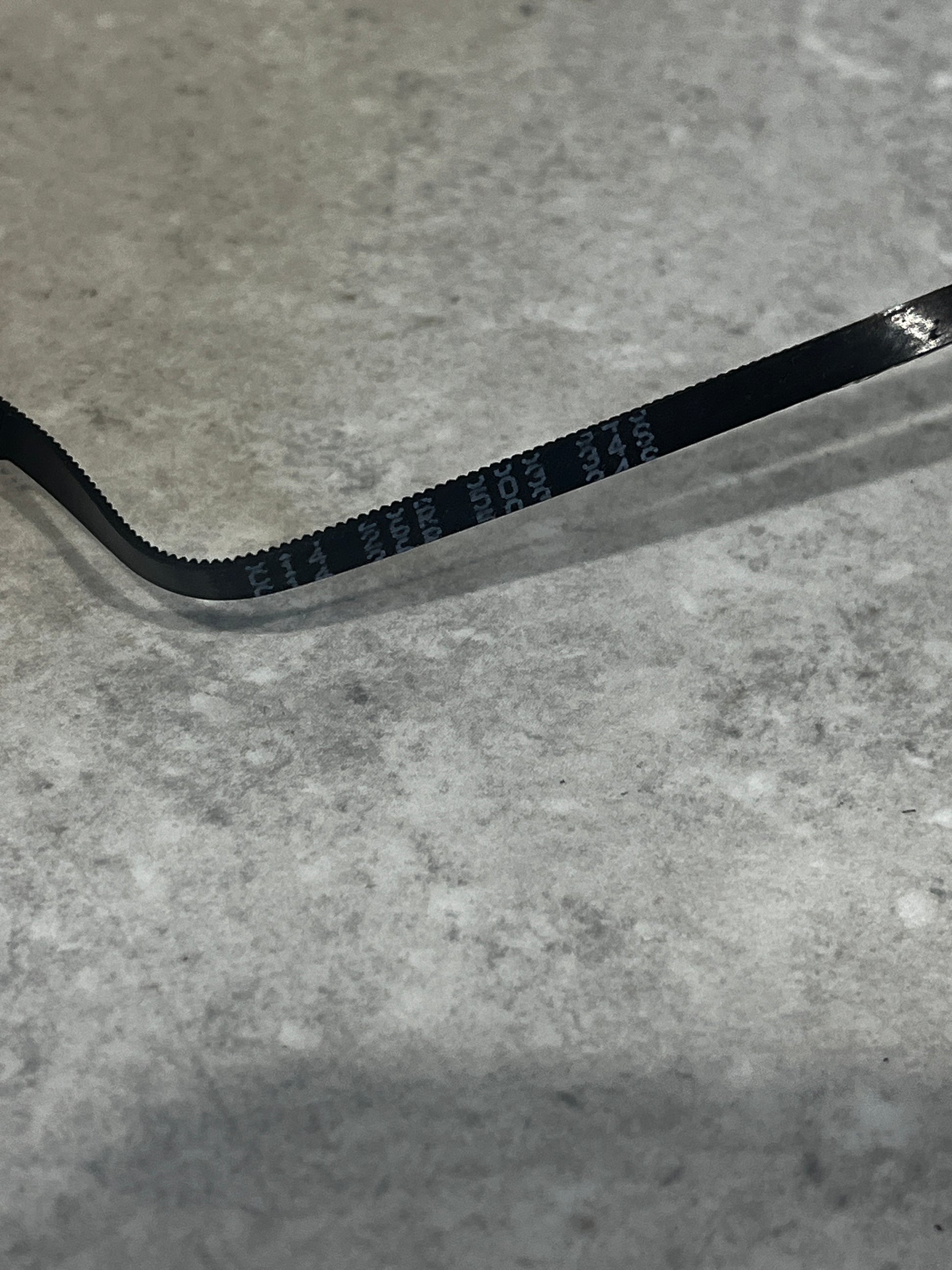 Close-up of the toothed rubber timing belt showing the fine teeth and material texture