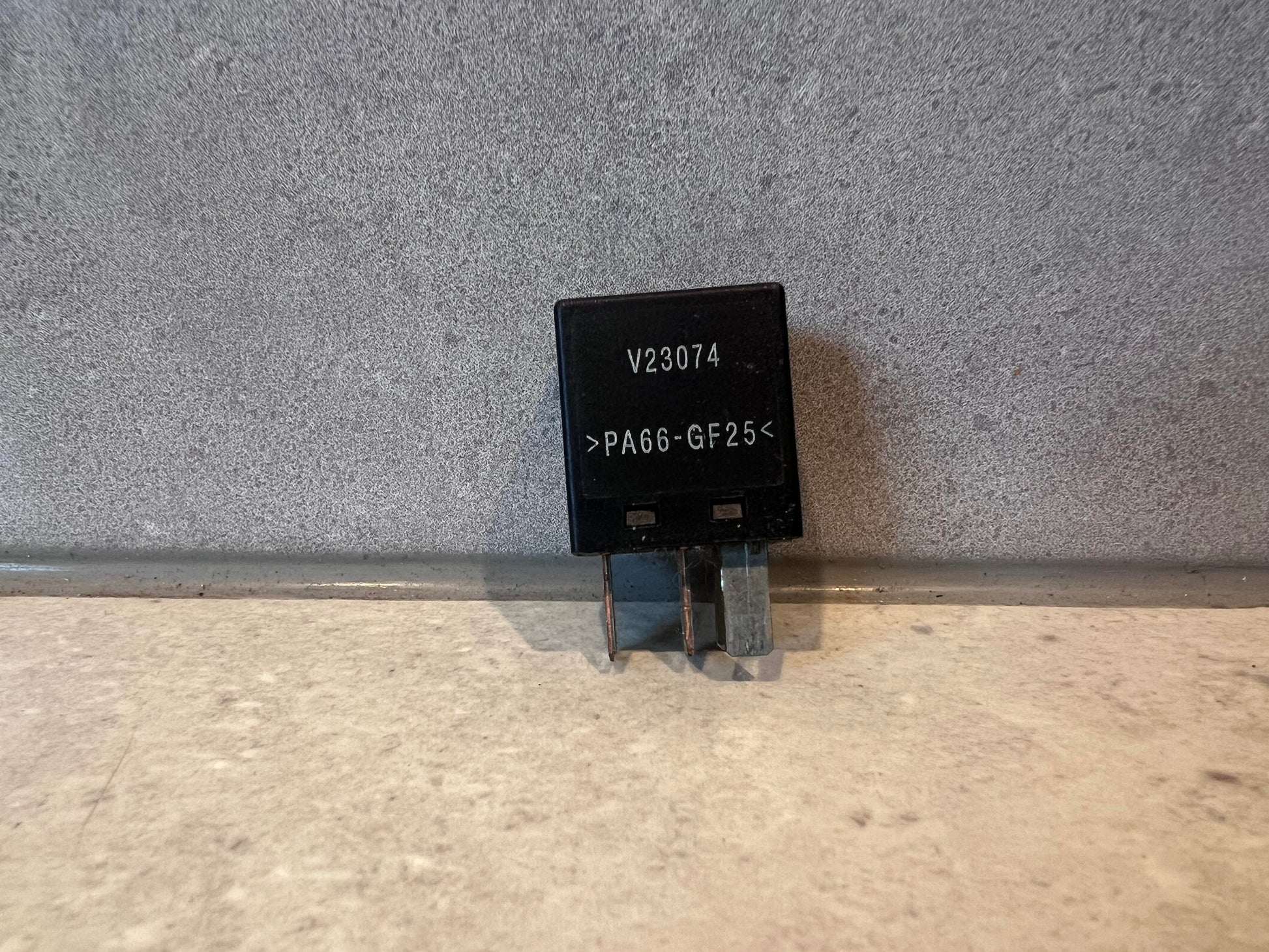 Black electrical relay with V23074 and PA66-GF25 marking
