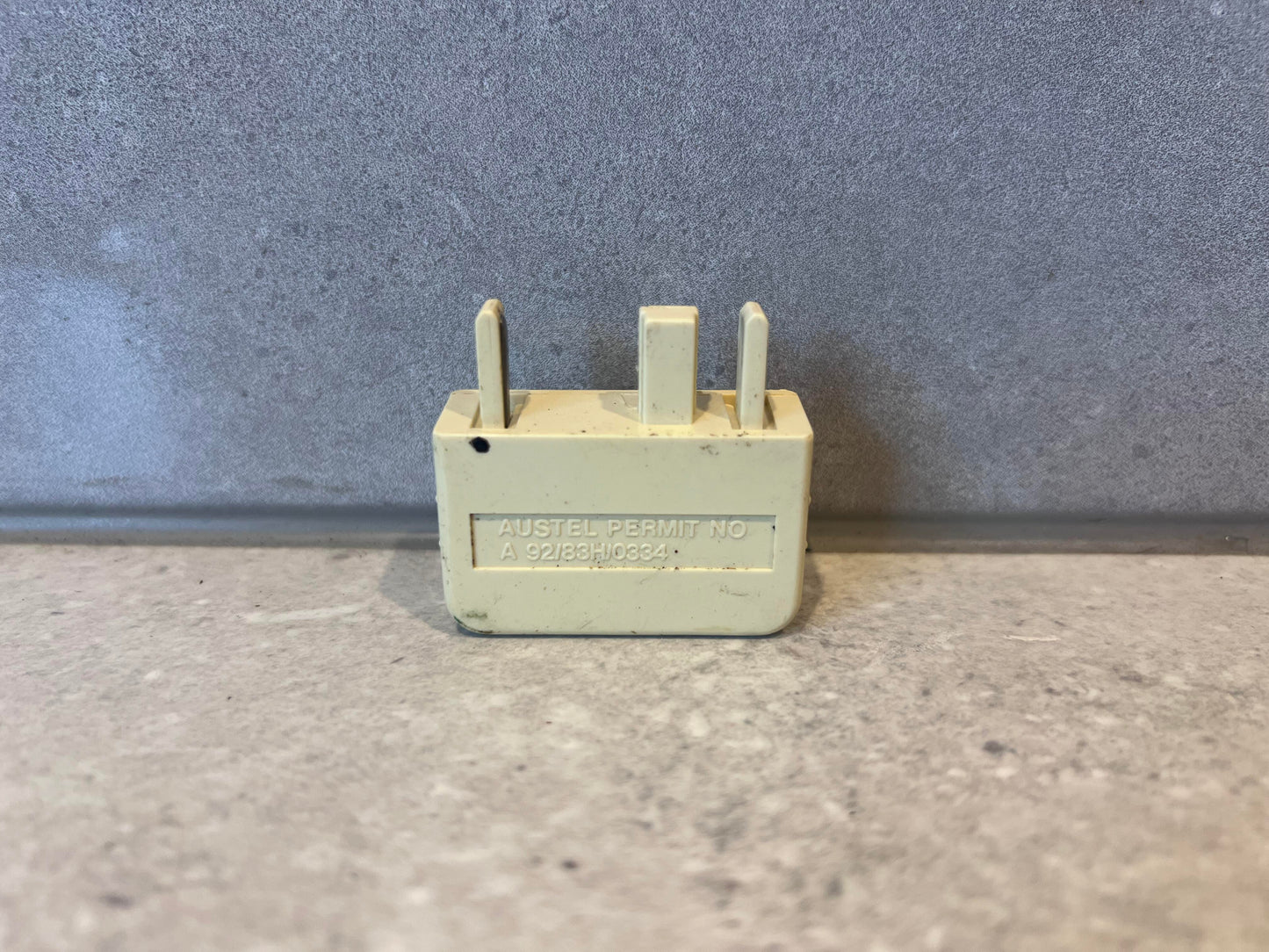 Australian telephone line adapter plug showing prongs and permit number