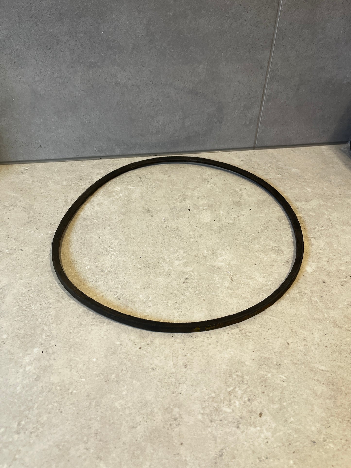 Black SPZ 1120 industrial V-belt on a light stone surface