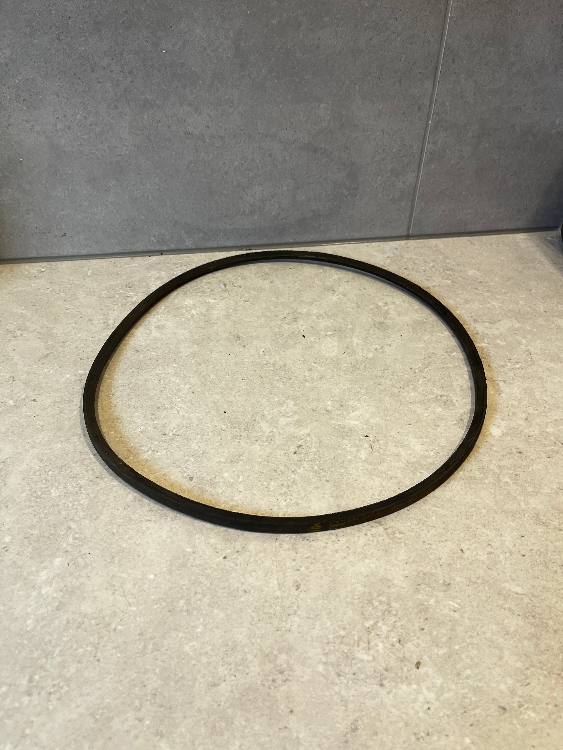 Black SPZ 1120 industrial V-belt on a light stone surface