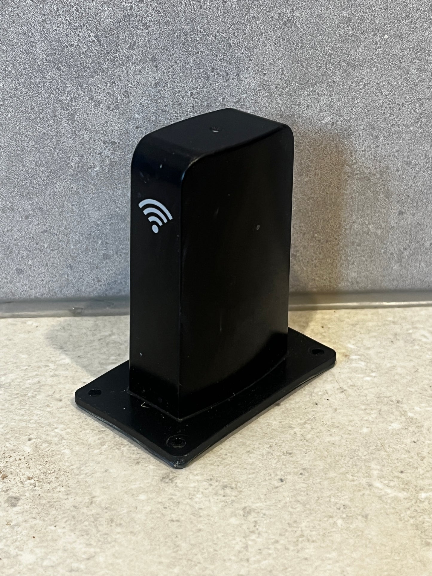 Black Wi-Fi receiver box with wireless signal icon on a countertop