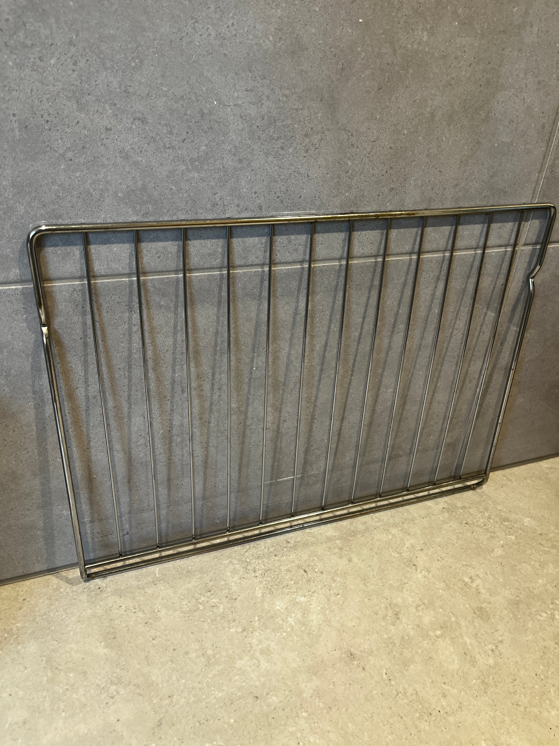 stainless steel oven rack resting against kitchen wall