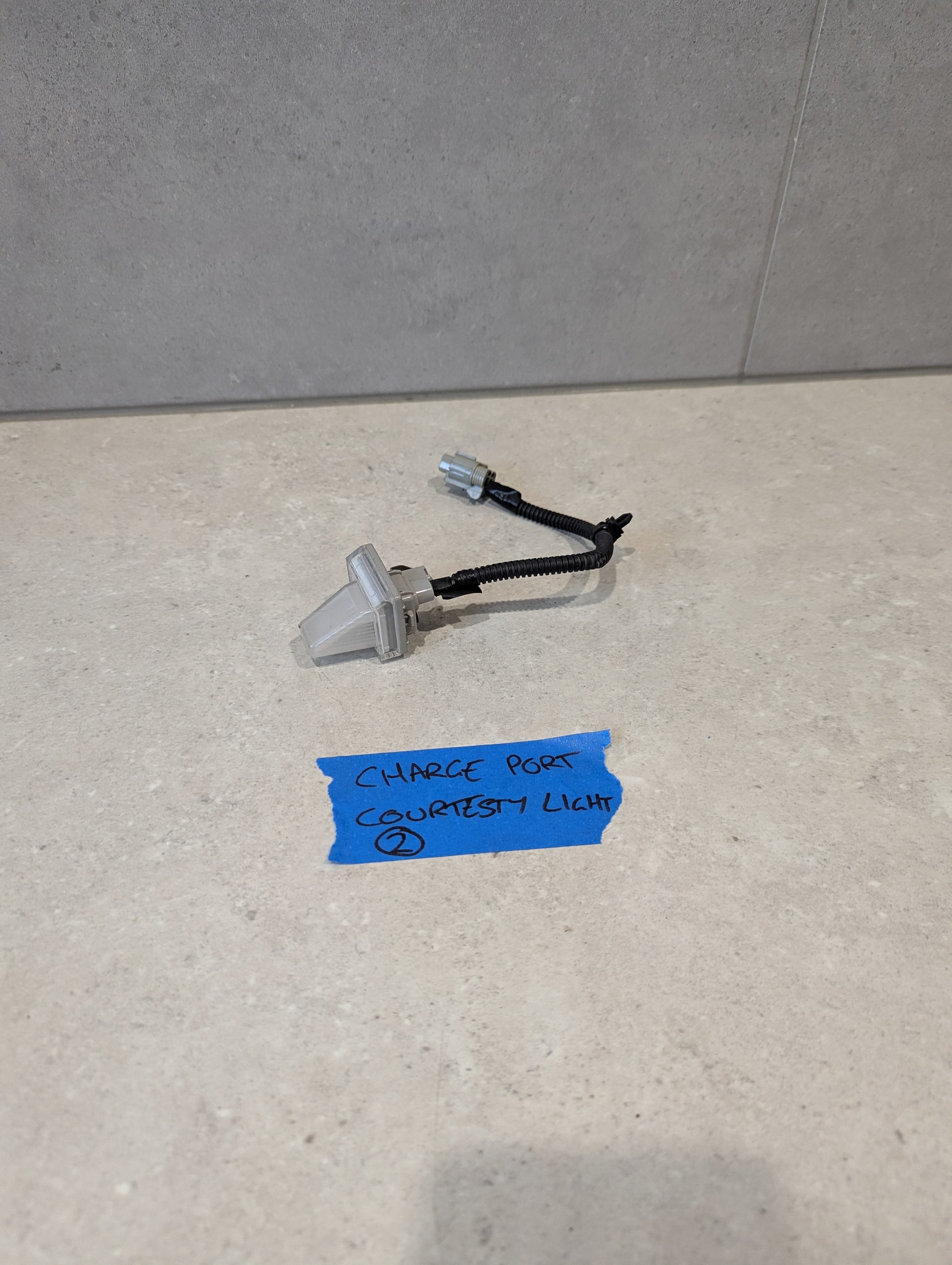 Charge port courtesy light with wiring harness on a light-colored surface