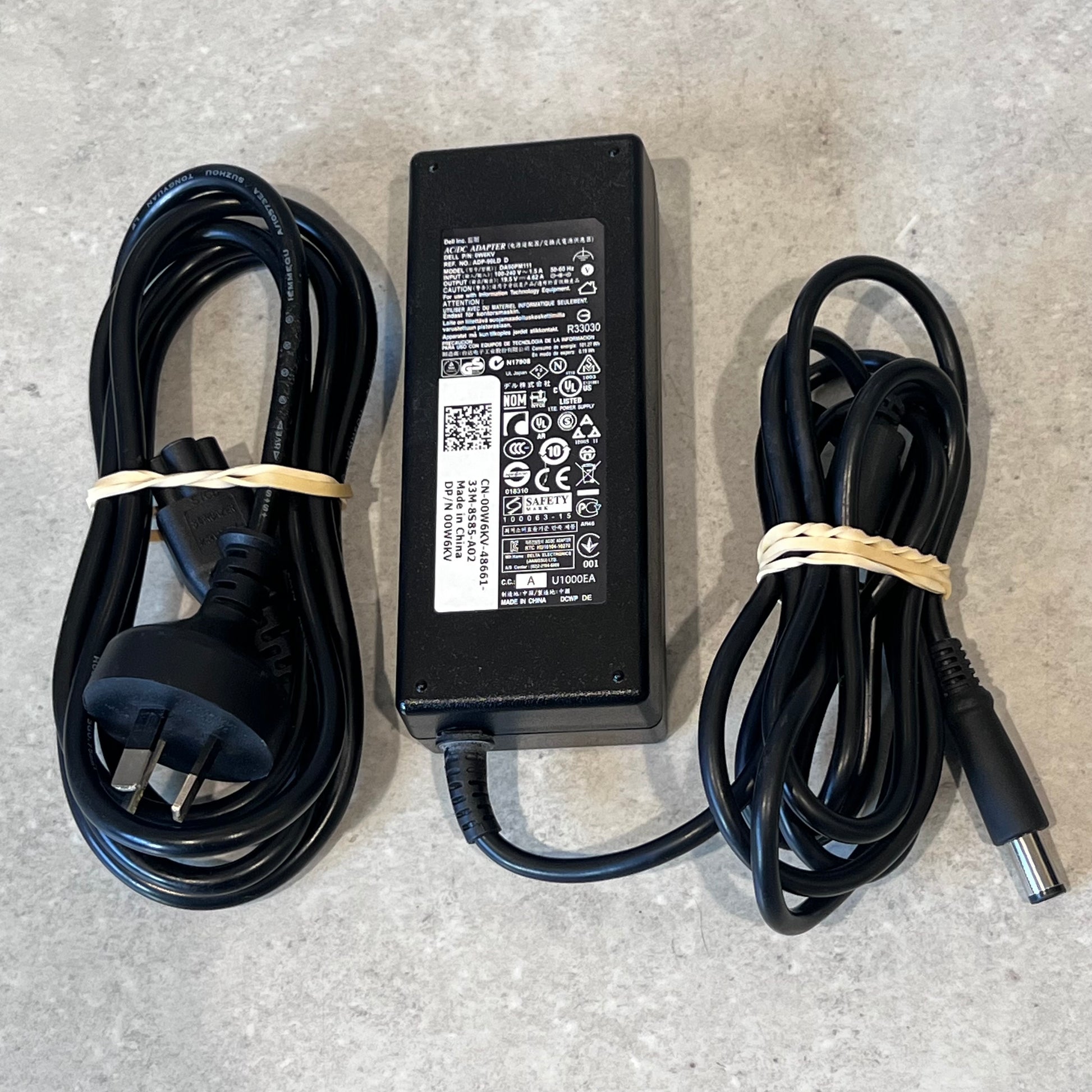 Dell 65W laptop power adapter with AC and DC charging cables on a gray surface