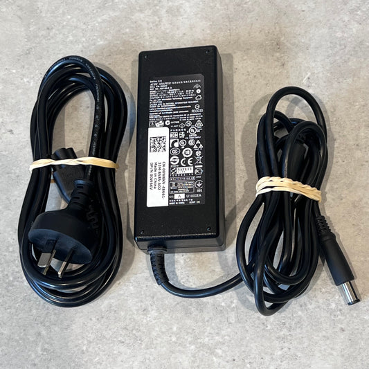 Dell 65W laptop power adapter with AC and DC charging cables on a gray surface