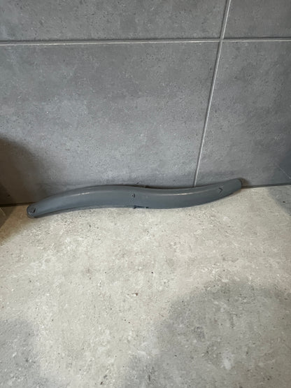 Curved grey plastic part on tiled surface