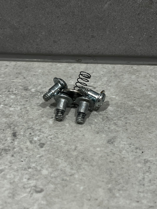 Set of metal screws and small coil spring on gray surface