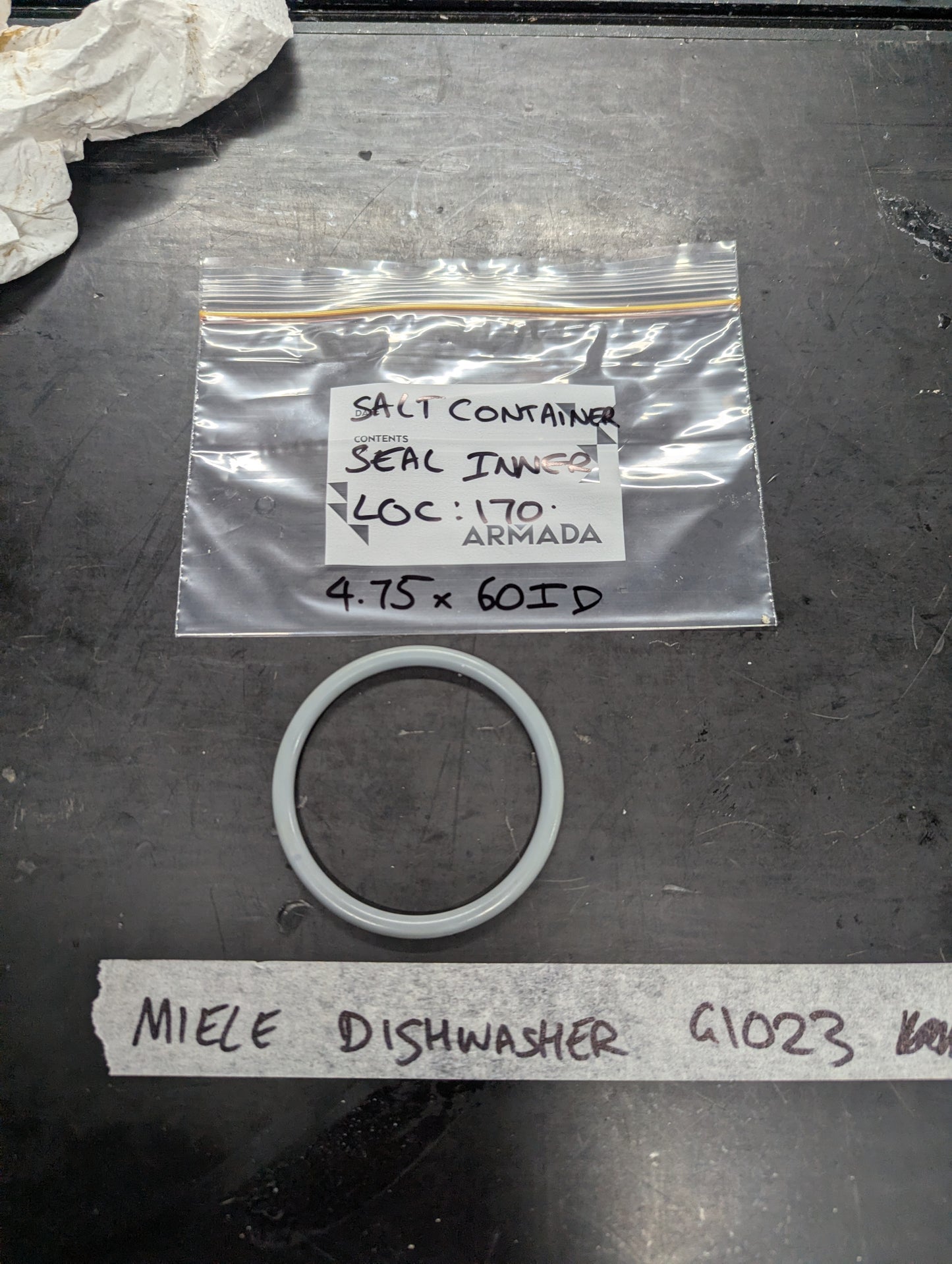 Gray circular seal and labeled bag for Miele dishwasher G1023 salt container