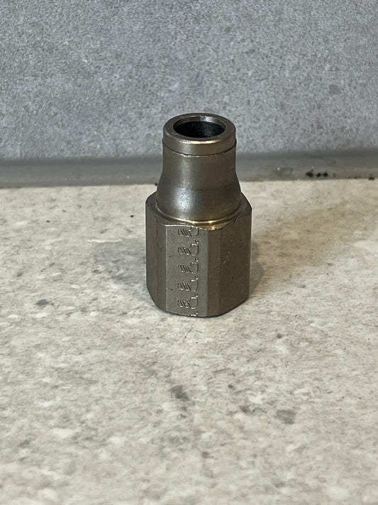 Steel hex hose fitting standing on a gray surface