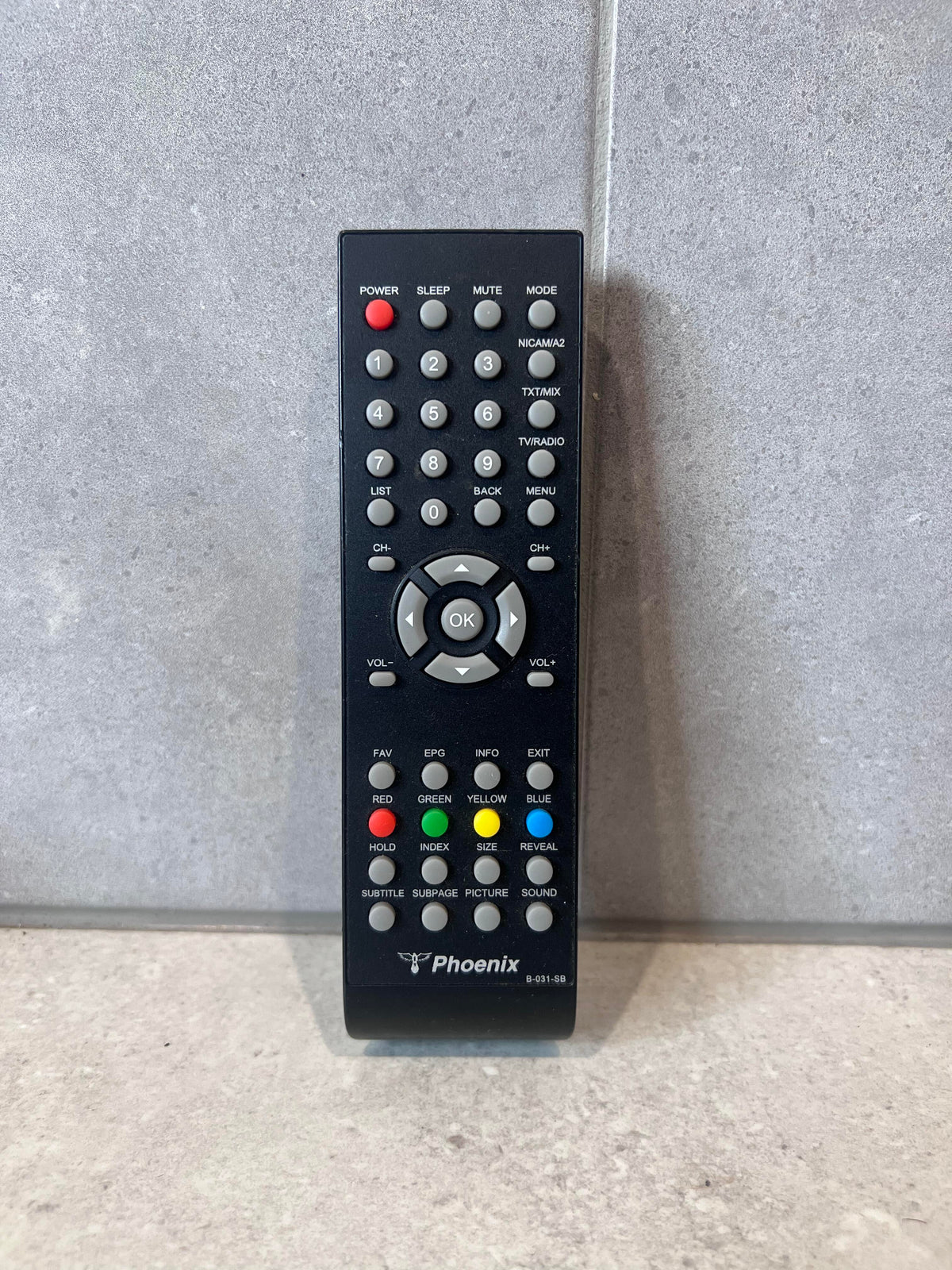 Phoenix Universal TV Remote Control with labeled buttons on a grey surface
