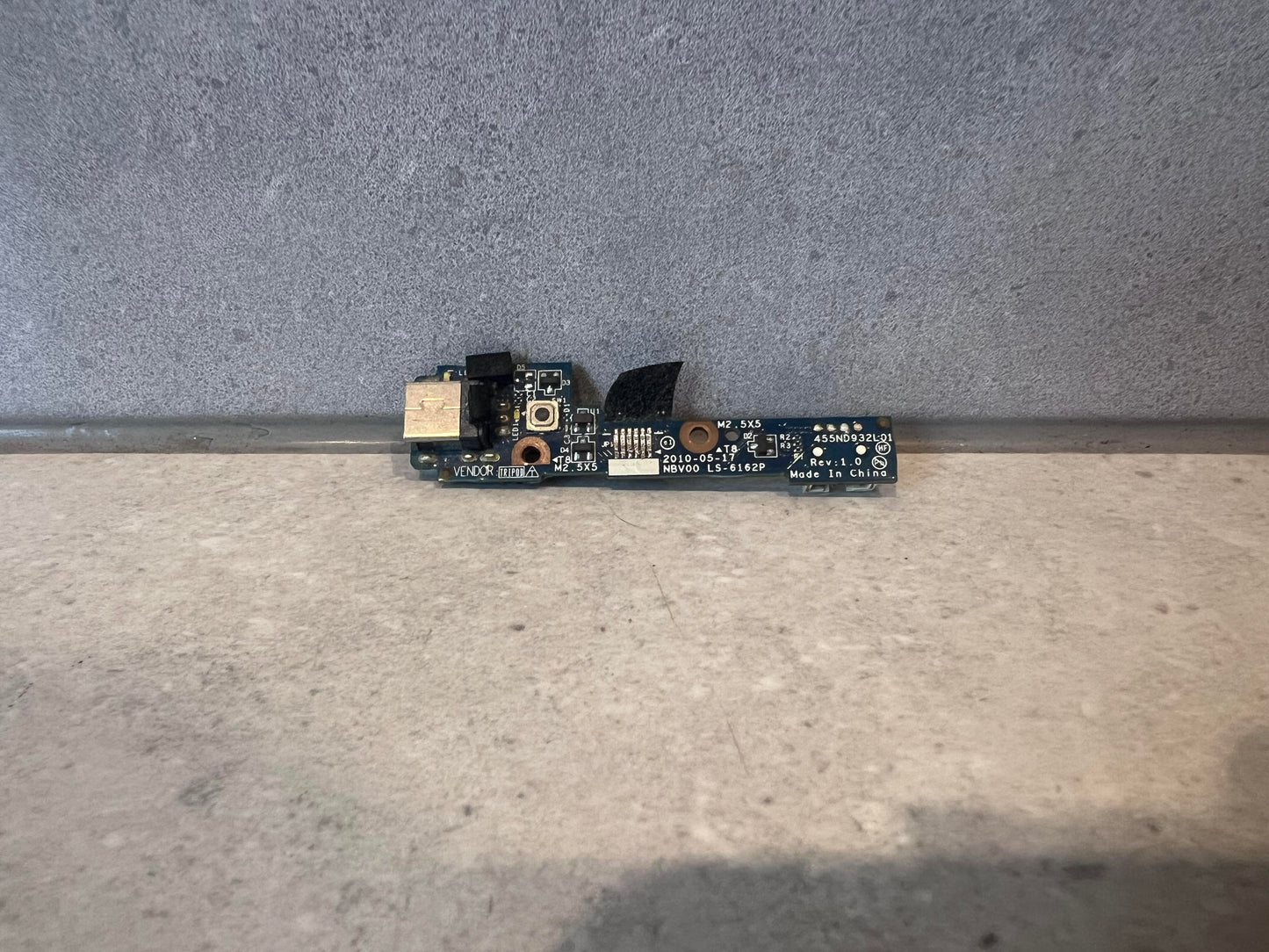 Laptop USB port circuit board on gray surface