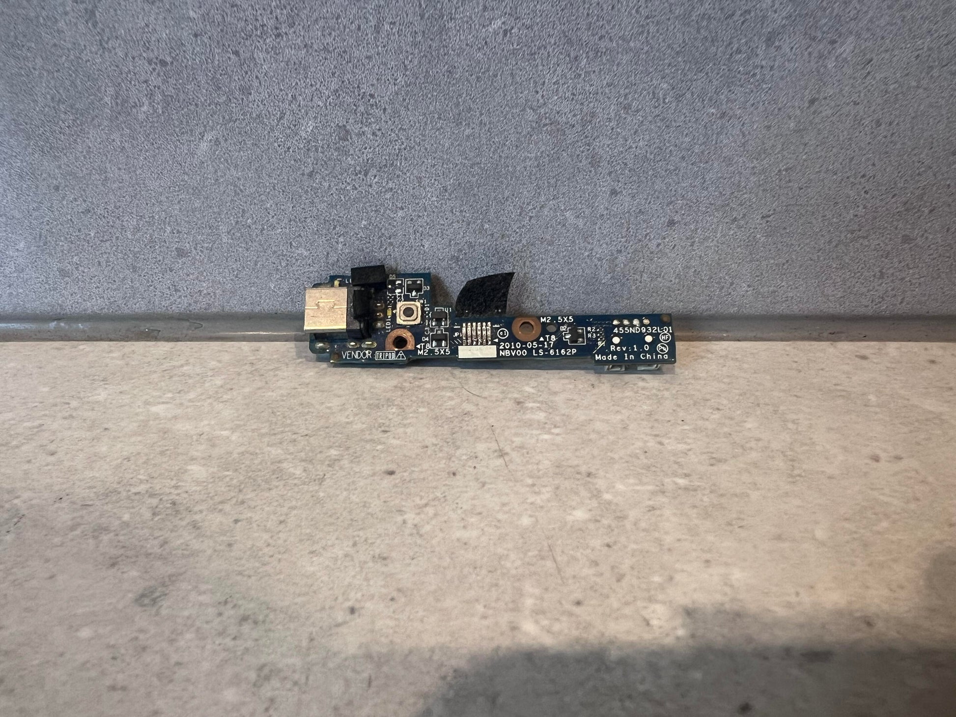 Laptop USB port circuit board on gray surface