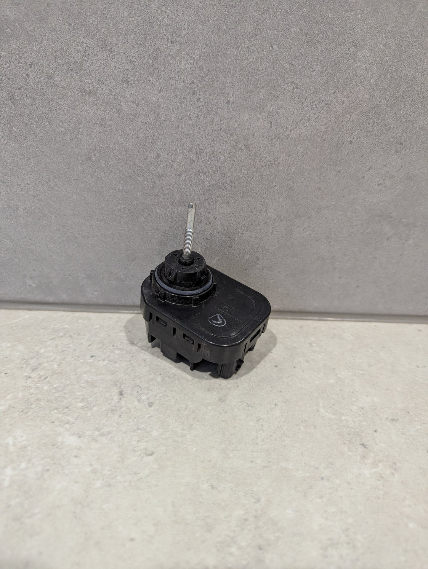 Nissan headlight leveling motor on a light surface