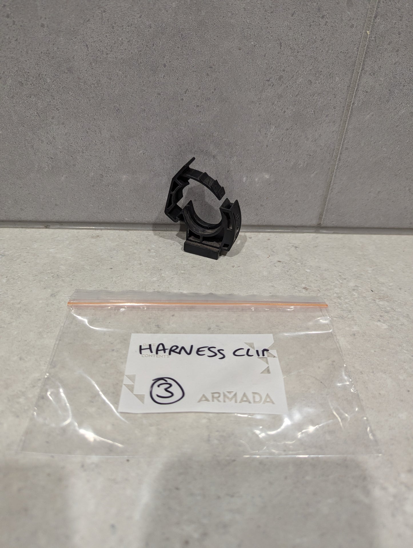 Armada black plastic harness clip and labeled storage bag