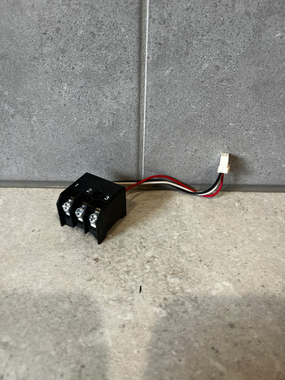 Three-wire terminal block connector with black housing and attached wires on a gray background