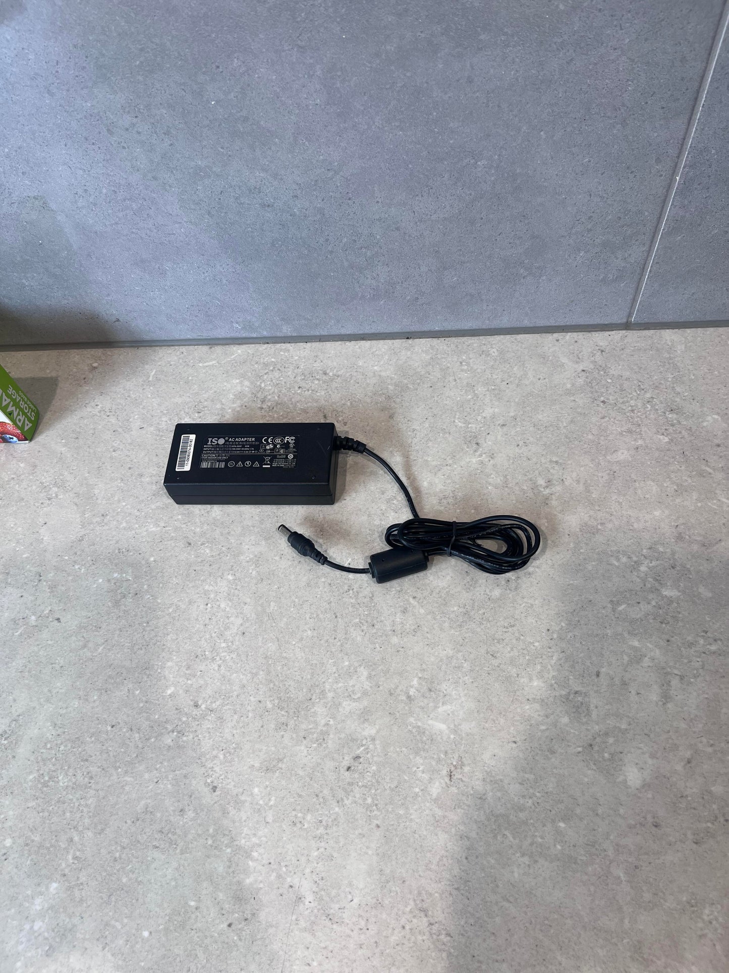 ISO 60W AC adapter with power cord on a light surface