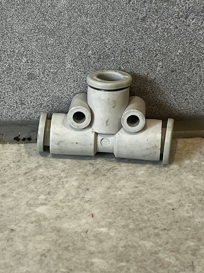Plastic pneumatic tube tee fitting connector on gray surface