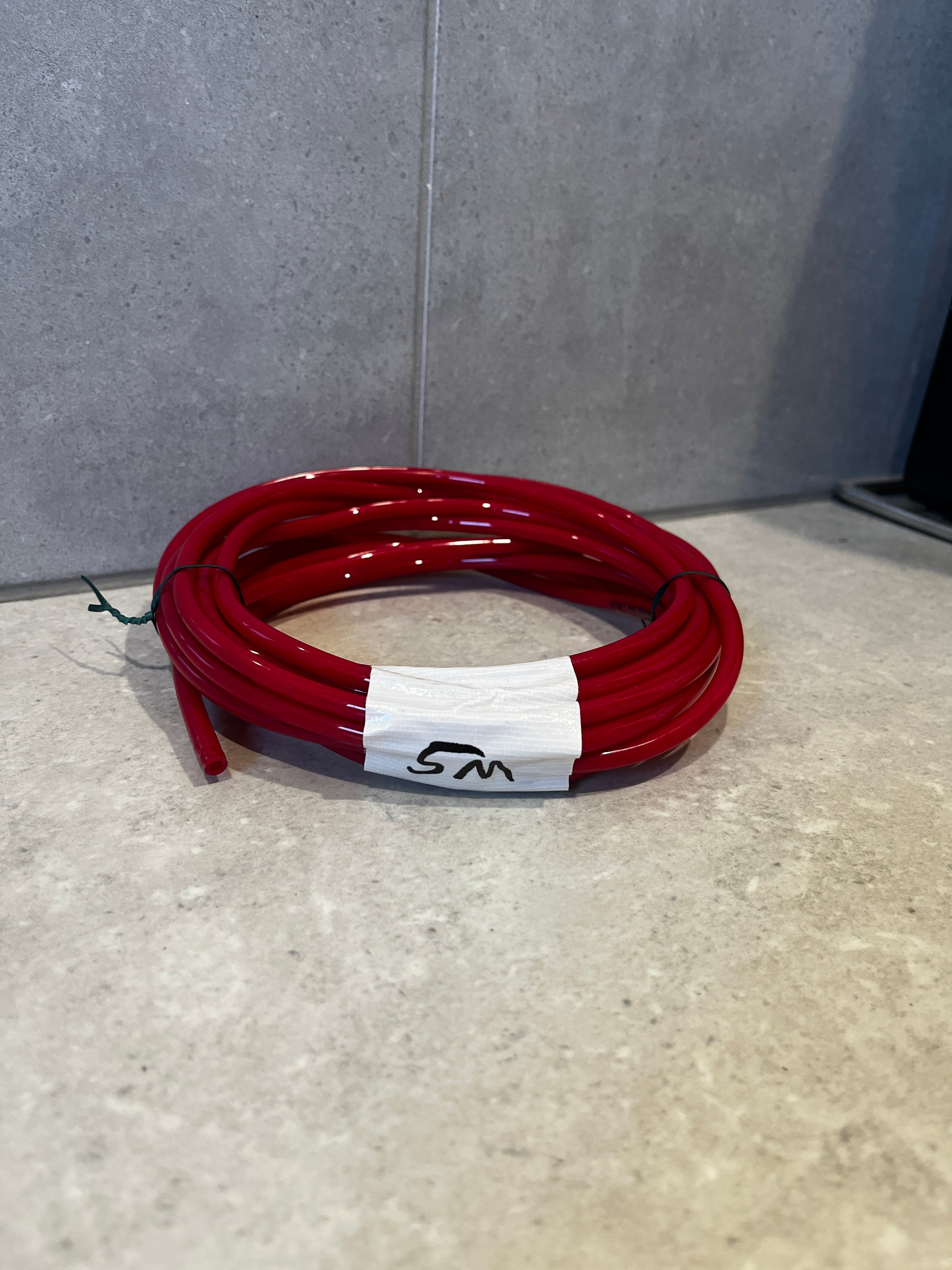Coiled red polyurethane tubing on countertop marked 5M