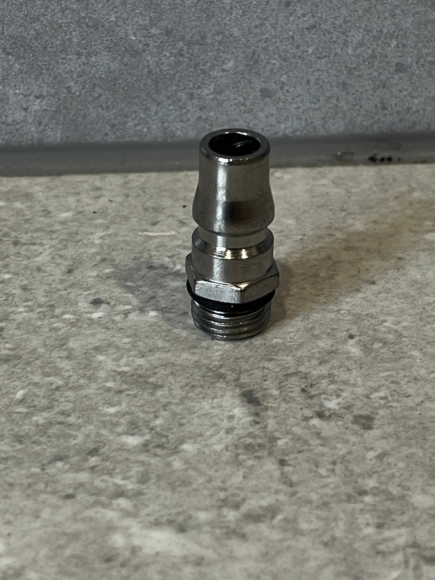 Stainless steel air compressor hose fitting on a stone surface