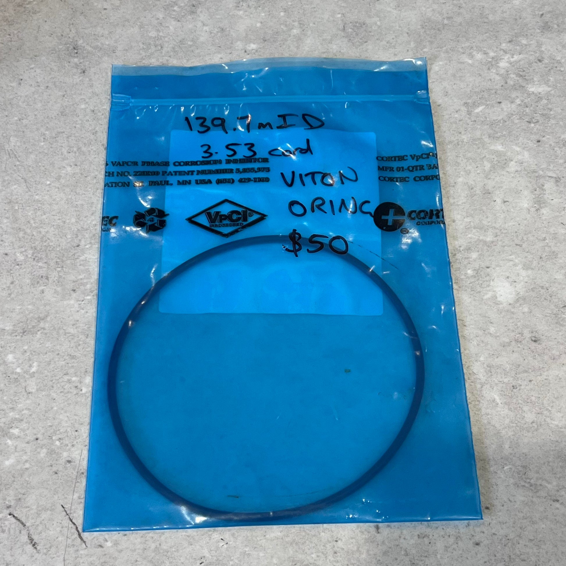 Viton O-ring with 139.7mm ID in blue VpCI packaging on gray surface