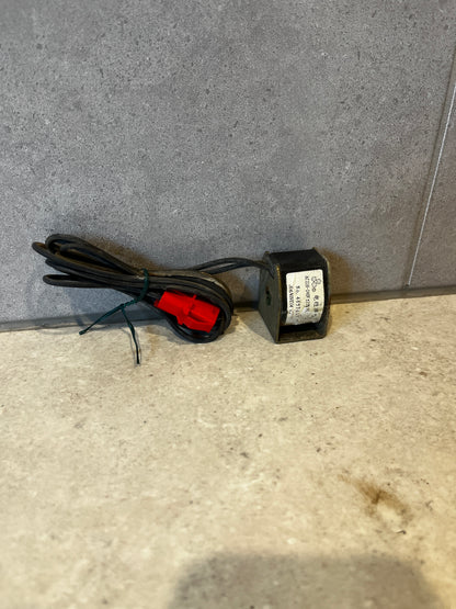 AC 220-240V electrical coil transformer with attached black cable and red connector on gray background