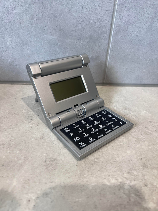 Open portable foldable world clock calculator showing digital display and keypad
