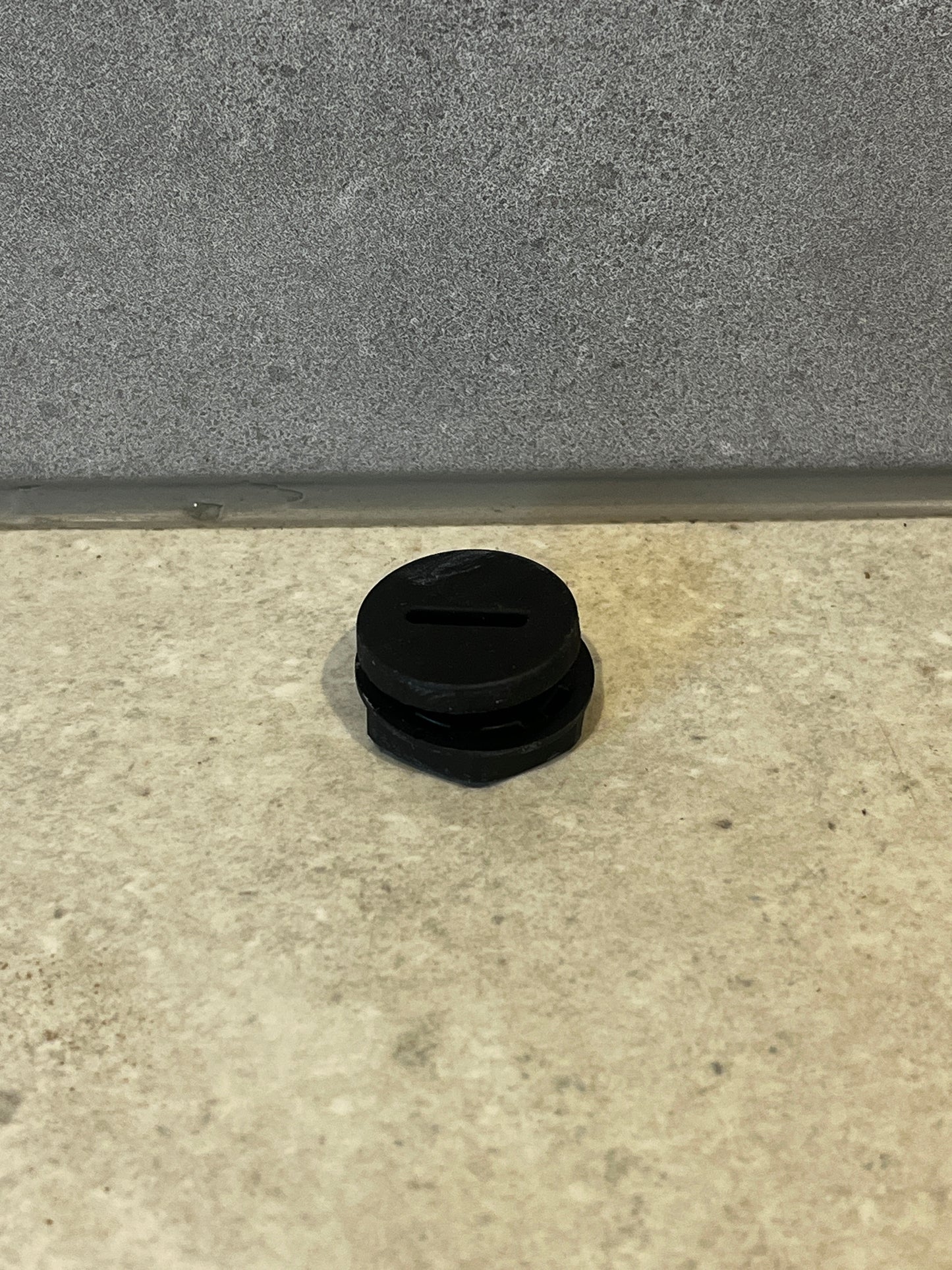 Round black rubber pipe plug on gray tile surface