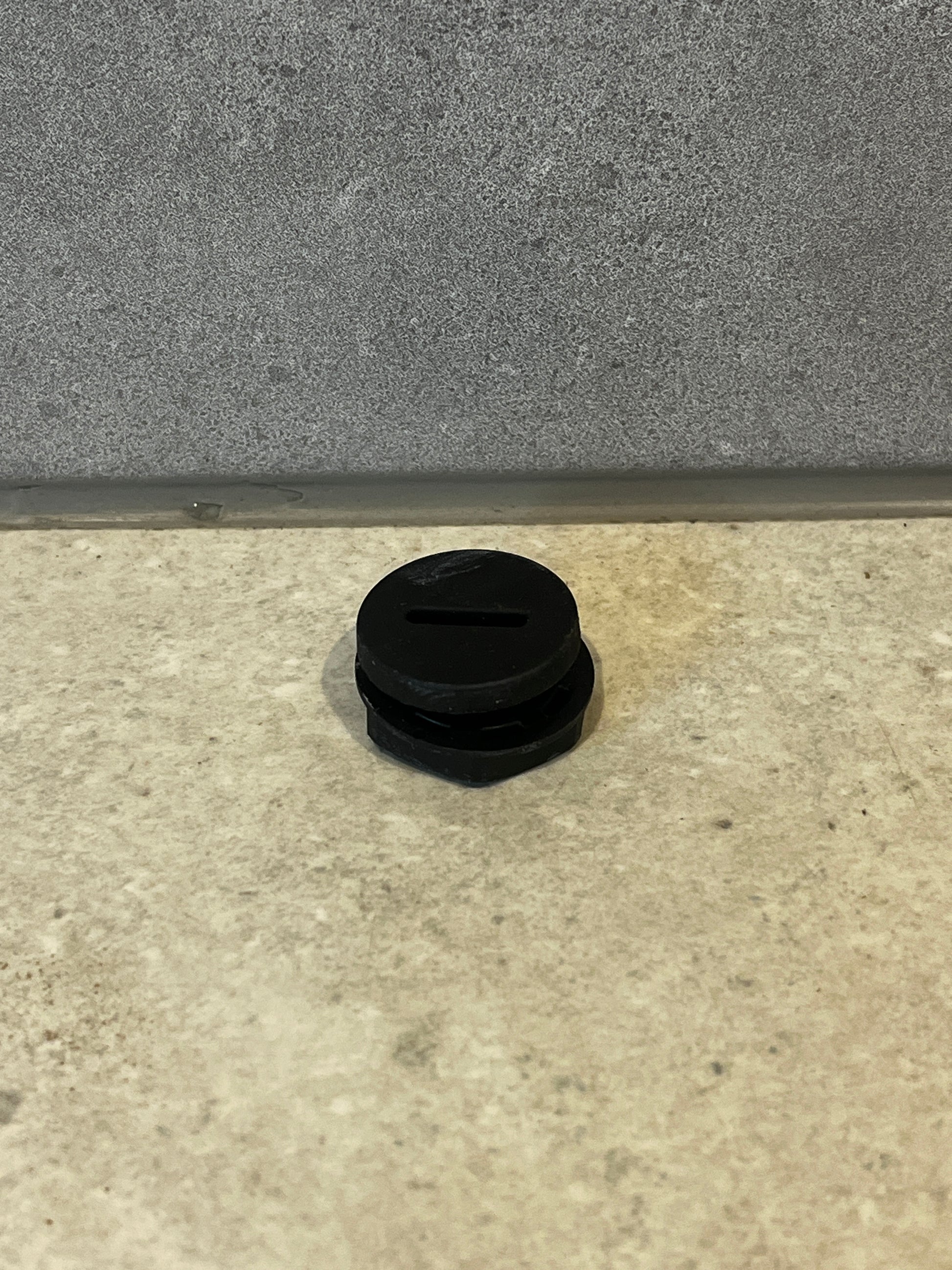 Round black rubber pipe plug on gray tile surface
