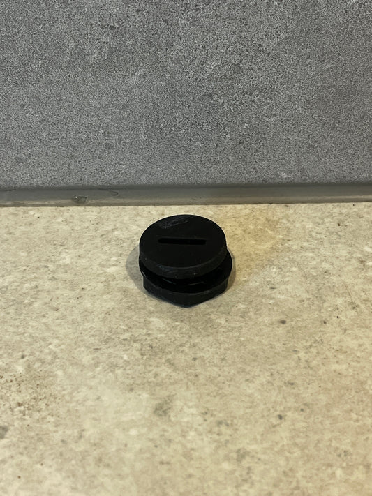Round black rubber pipe plug on gray tile surface