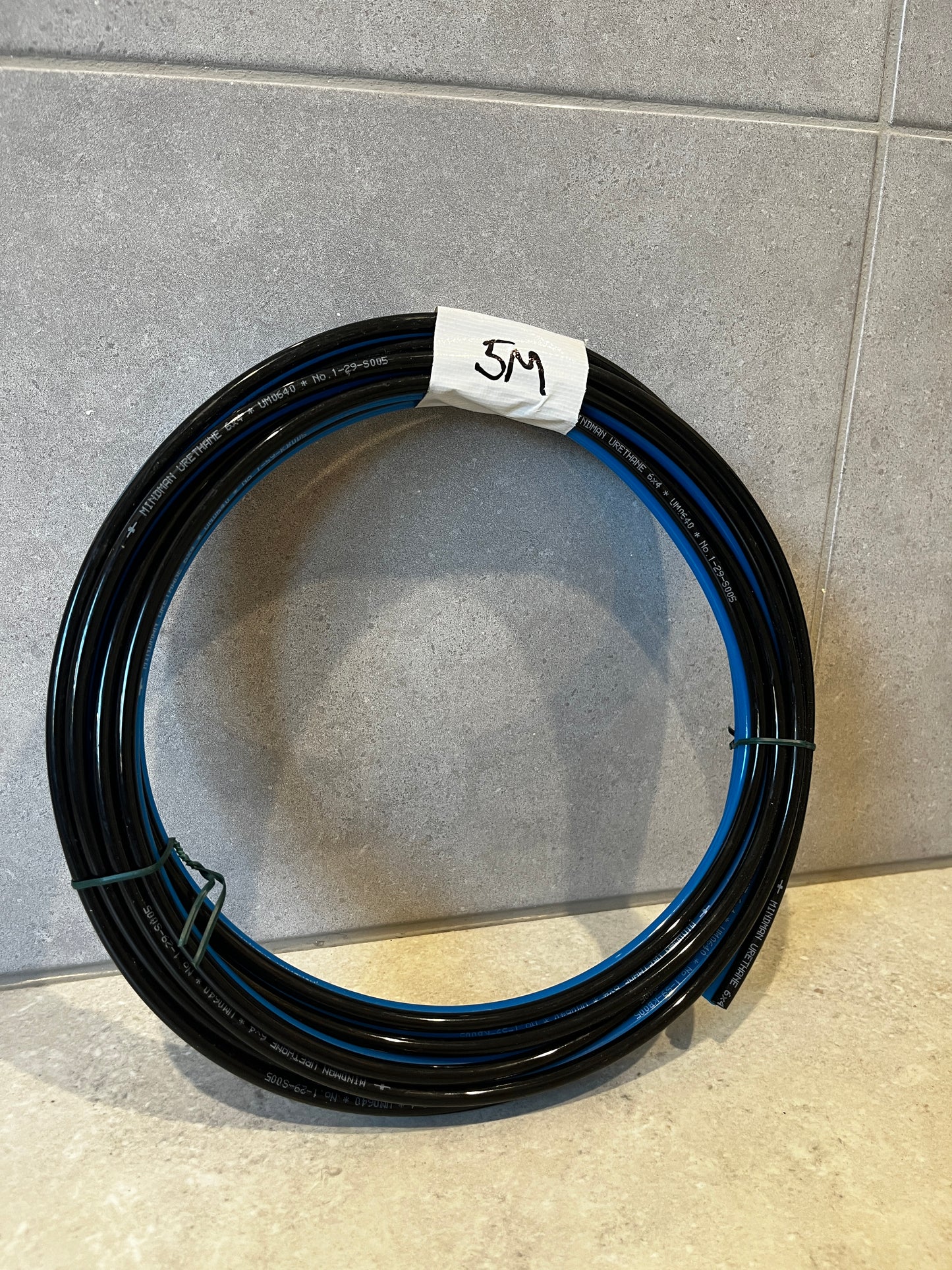 Coiled 5-meter black urethane air hose tube with blue stripe wrapped with a label marked 5M